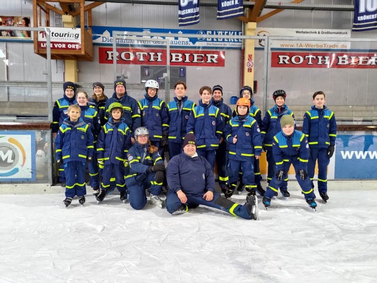 Jugendgruppe mit blauen Uniformen auf der Eisbahn mit Schlittschuhen