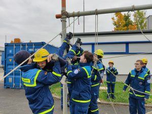 Junghelfer heben einen anderen Junghelfer durch ein Netz aus Leinen
