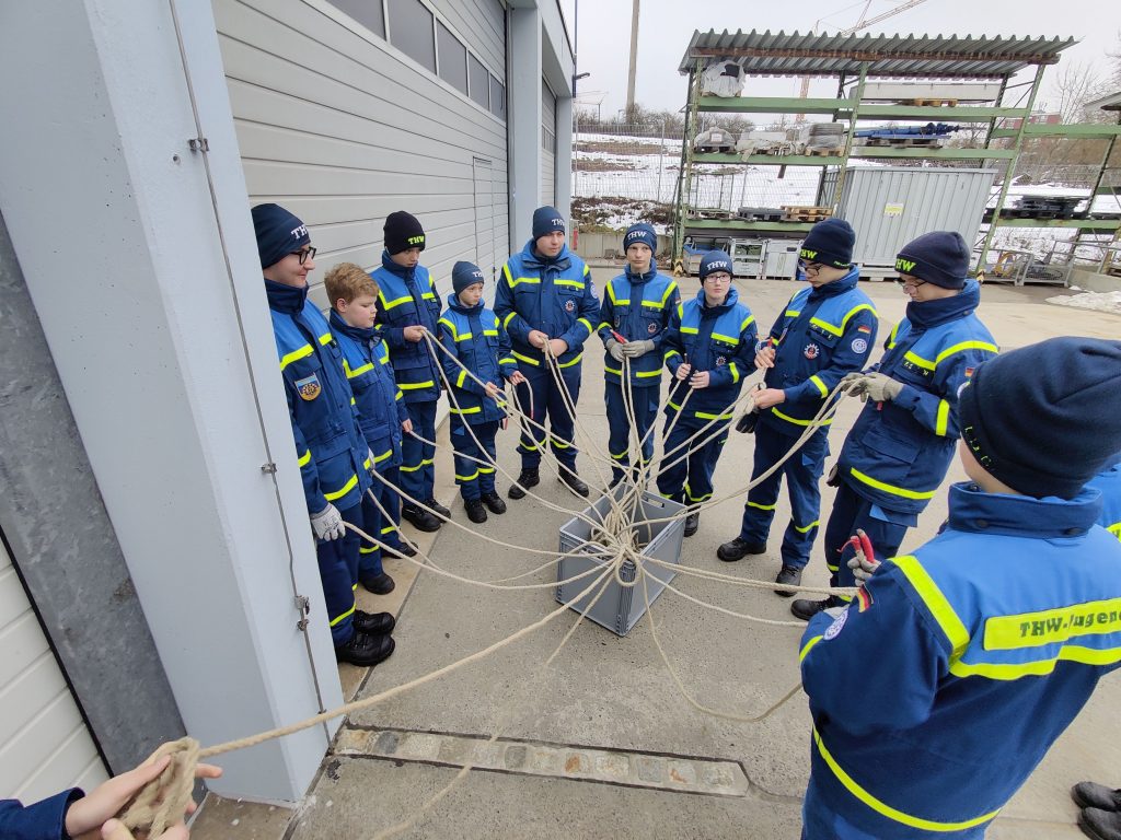 Viele Junghelfer stehen im Kreis um ein Knäusel aus Leinen, jeder eine Leine in der Hand