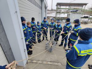 Viele Junghelfer stehen im Kreis um ein Knäusel aus Leinen, jeder eine Leine in der Hand