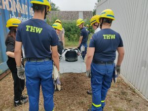 Junghelfys tragen eine Trage mit einem Wassereimer